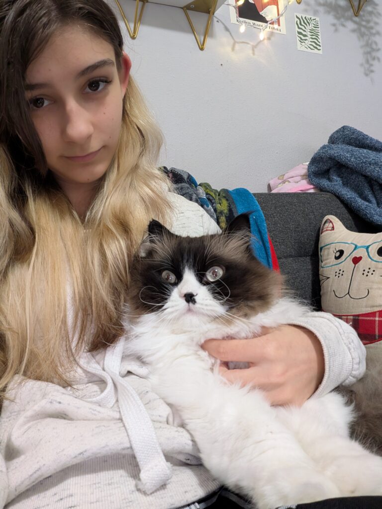 A photo of Echo sitting on a couch holding one of her cats