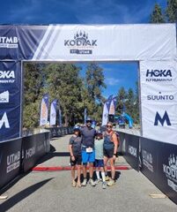 A man and woman stand with two children underneath a banner.