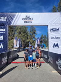 A man and woman stand with two children underneath a banner.